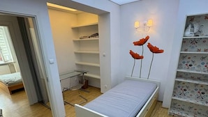 Ein Schlafzimmer mit einem Bett, einem Kleiderschrank und einem Regal mit Dekorationen.