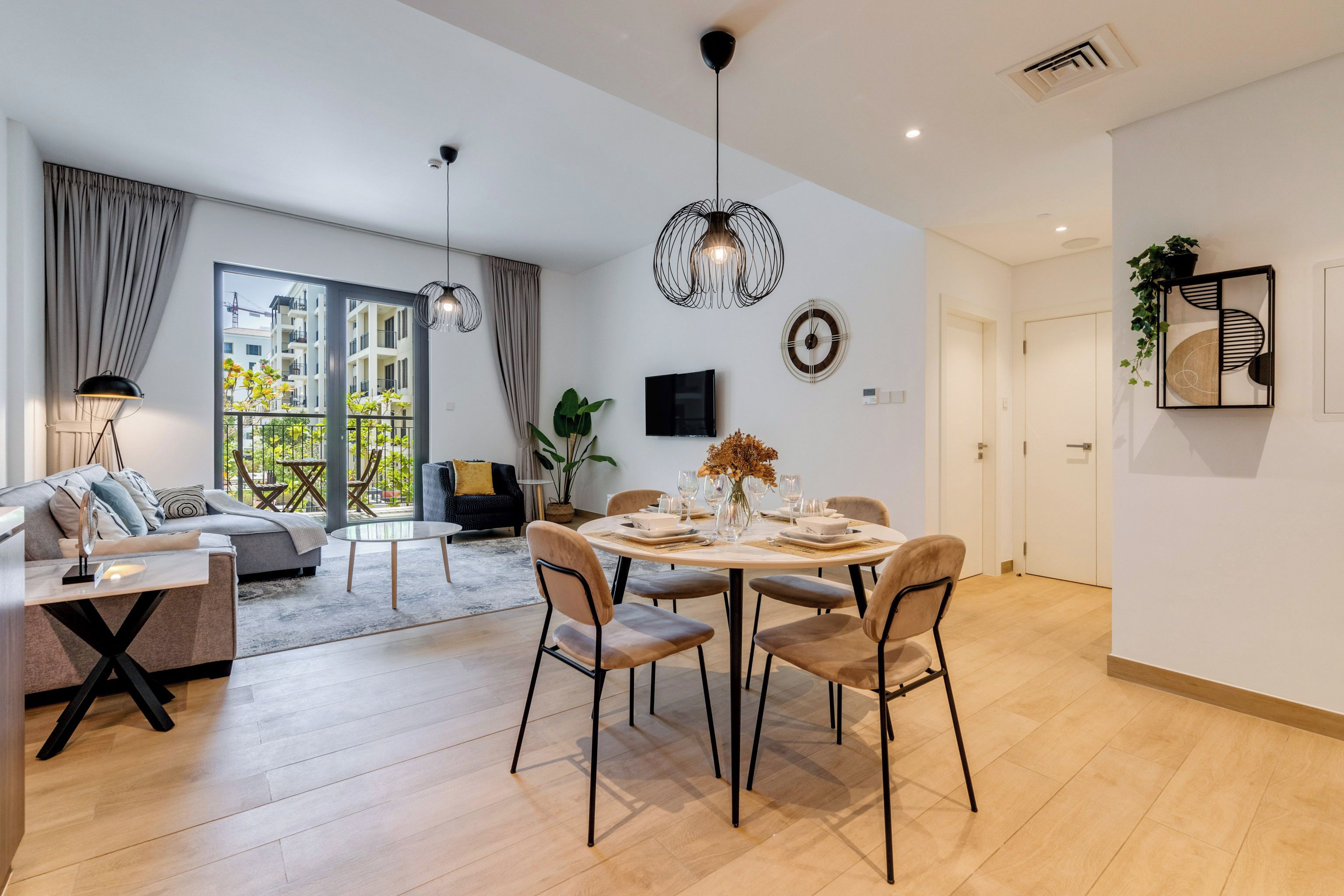 Un salon moderne avec un canapé, une table à manger pour quatre personnes et une grande fenêtre agrémentée de rideaux.