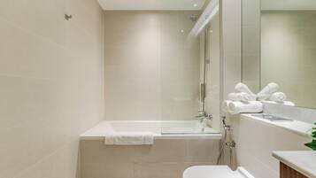 A modern bathroom with a bathtub, a toilet, and a shower area.