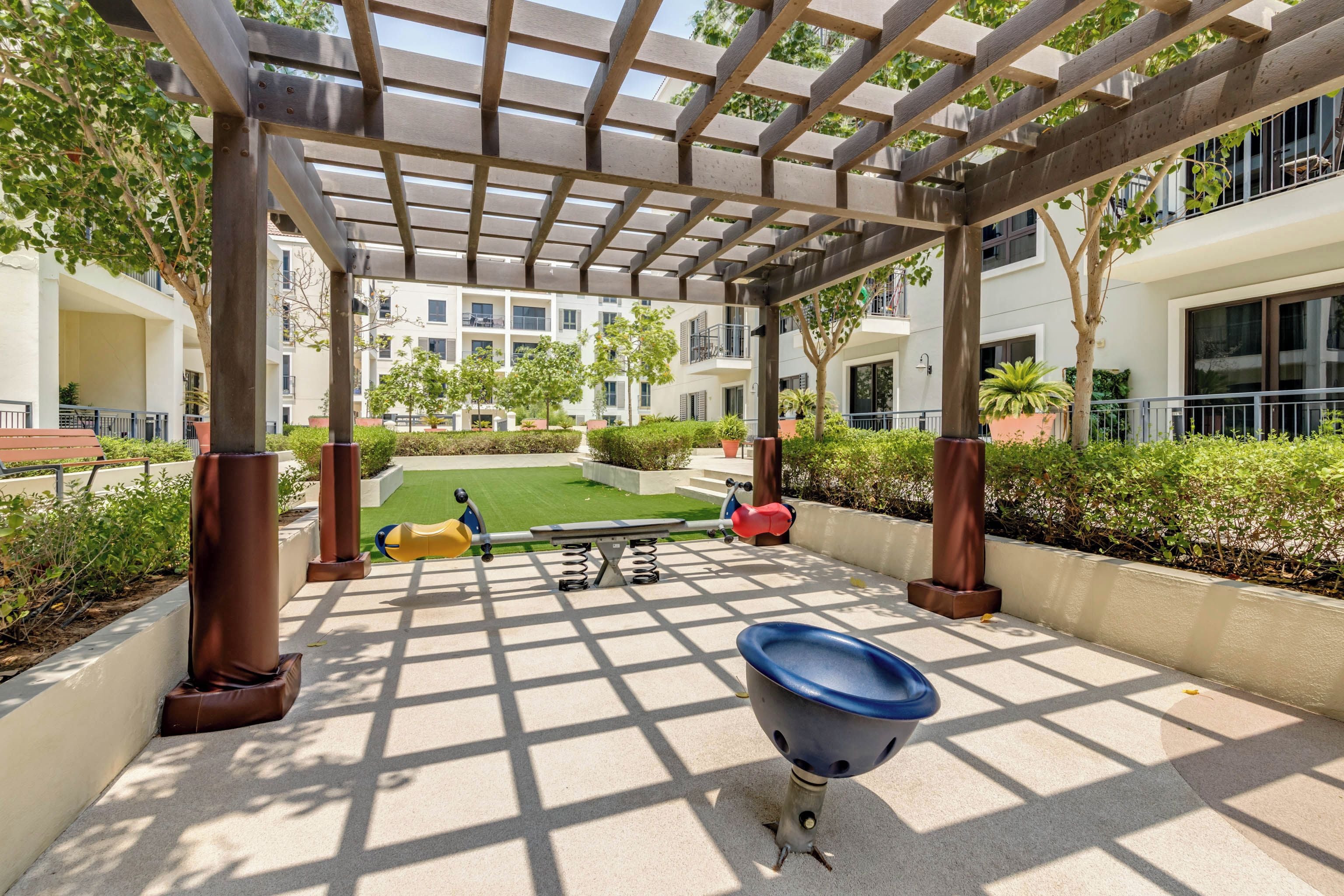 An outdoor patio area with a pergola, exercise equipment, and a blue exercise ball.