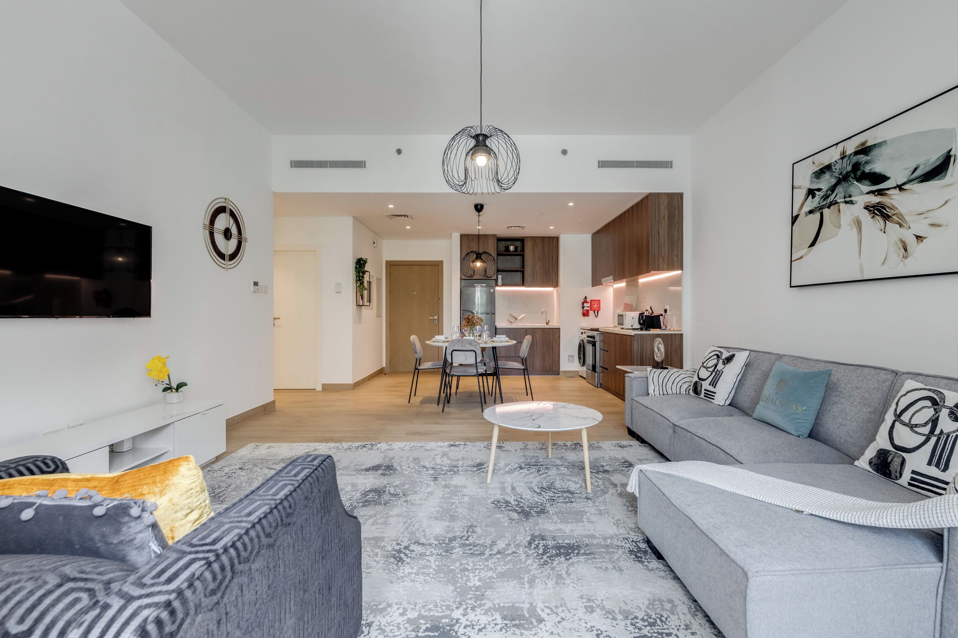 A modern living room with a grey sofa, a coffee table, and a flat-screen TV.