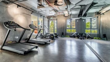 Een fitnessruimte met loopbanden, crosstrainers en gewichten.