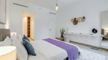 A modern bedroom with a bed, bedside tables, a mirror, and a wall-mounted light fixture.