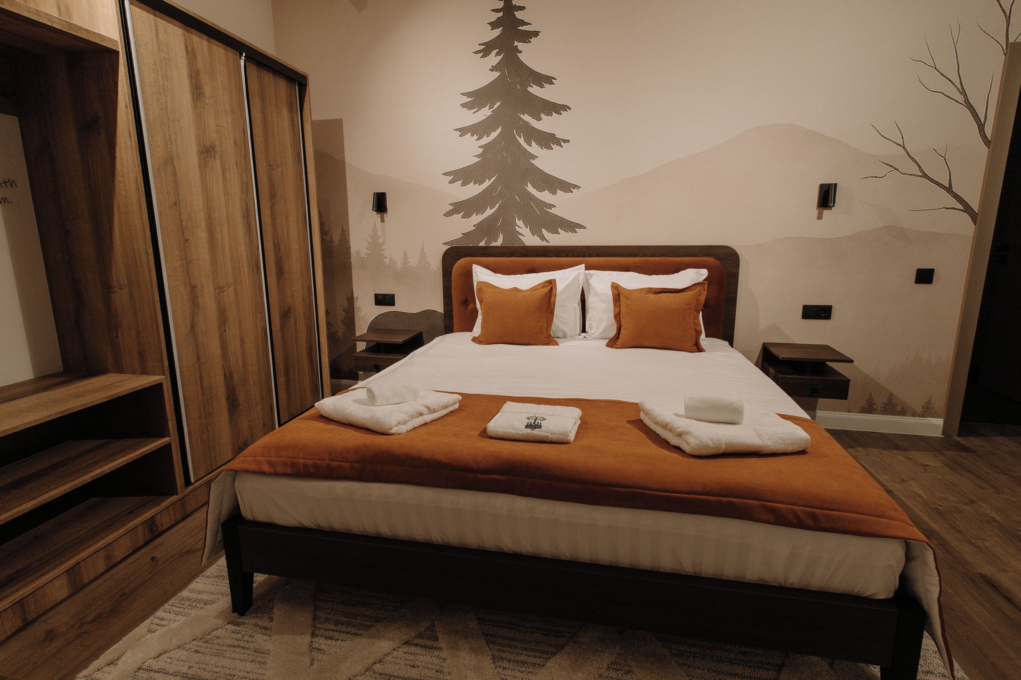Ein Hotelzimmer mit einem großen Bett, einem Holzschrank und einer Wandmalerei zum Thema Berge.