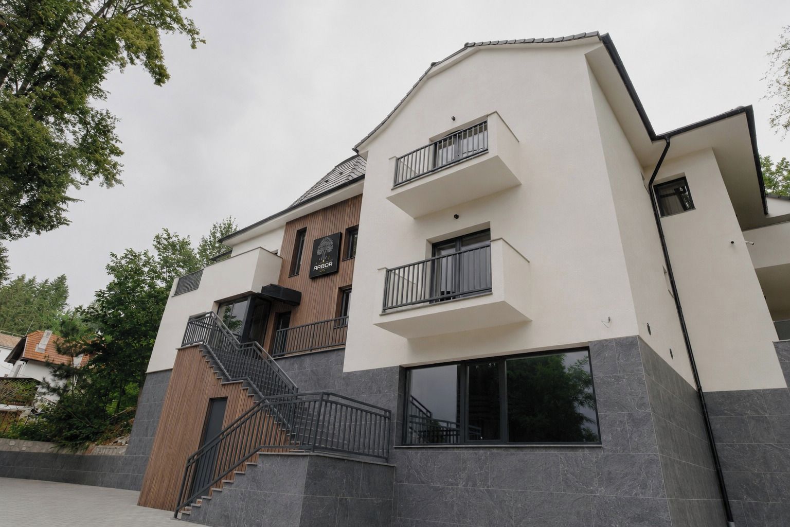 Un bâtiment moderne à deux étages, doté d’une façade en bois, d’un balcon et d’un escalier.