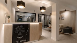 A hotel reception area with a reception desk, two pendant lights, and a modern interior design. - Arbor Hotel (Sovata)