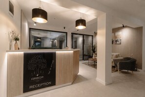 A hotel reception area with a reception desk, two pendant lights, and a modern interior design. - Arbor Hotel (Sovata)