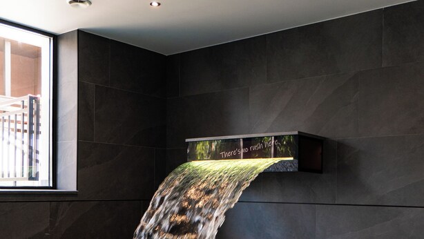 A pool with a waterfall feature, dark walls, and a window on the left. - Arbor Hotel (Sovata)
