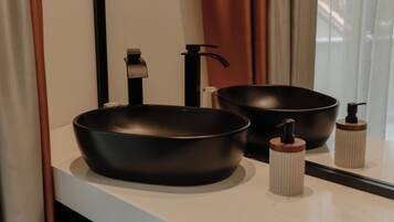 A bathroom with two black vessel sinks, a faucet, and a soap dispenser on the counter.