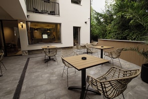 Un patio al aire libre con mobiliario de mimbre y vistas a un edificio con un ventanal grande.