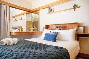 Ein Hotelzimmer mit Bett, Nachttisch, Spiegel und einem Fenster mit Vorhängen.