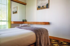 Ein Hotelzimmer mit einem Bett, einem Nachttisch, einem Spiegel und zwei Wandgemälden.