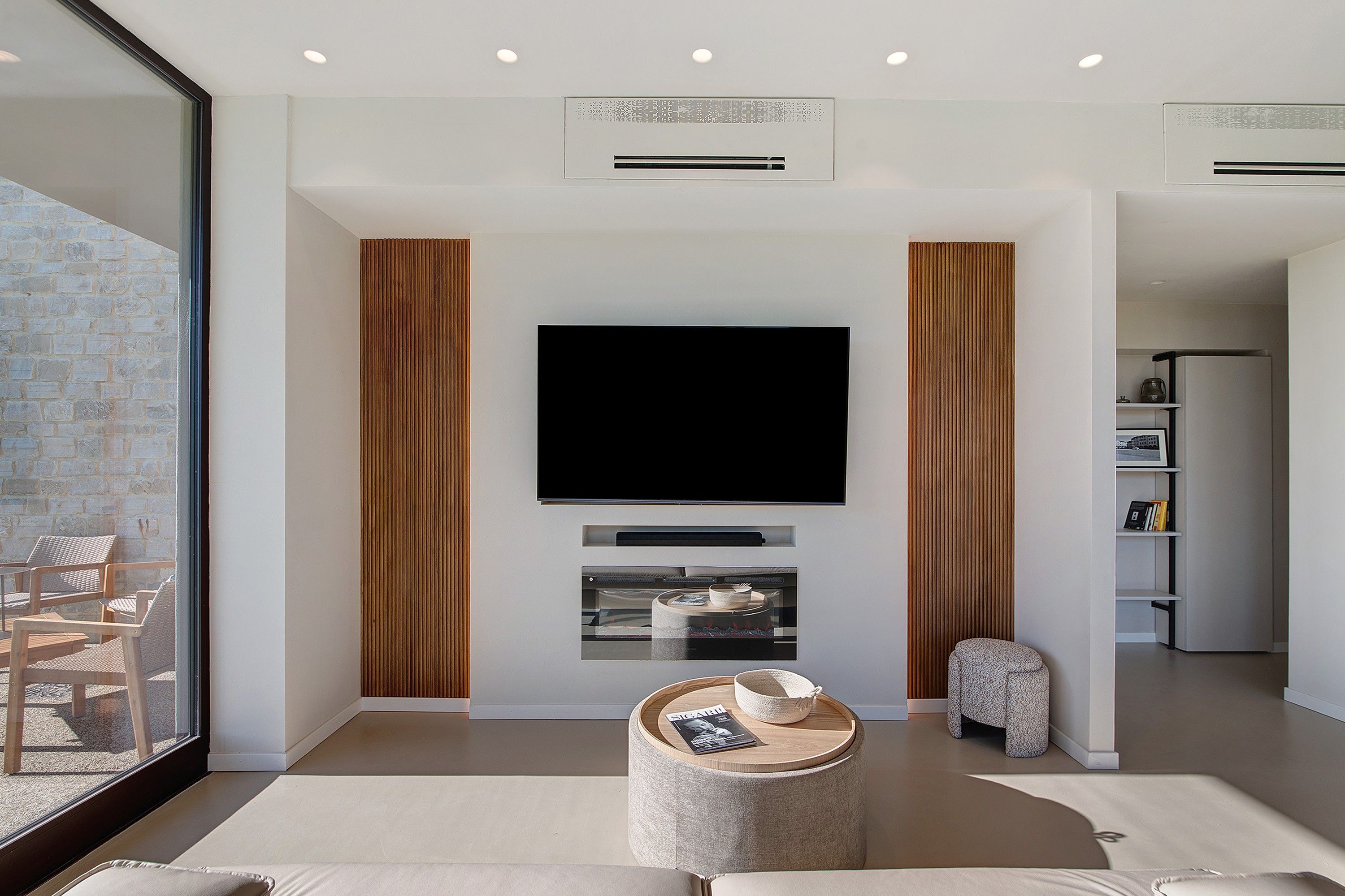 A modern living room with a flat-screen TV, a round coffee table, and a seating area.