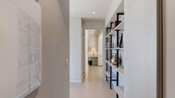 A hallway with a bookshelf, a door leading to another room, and a lamp.