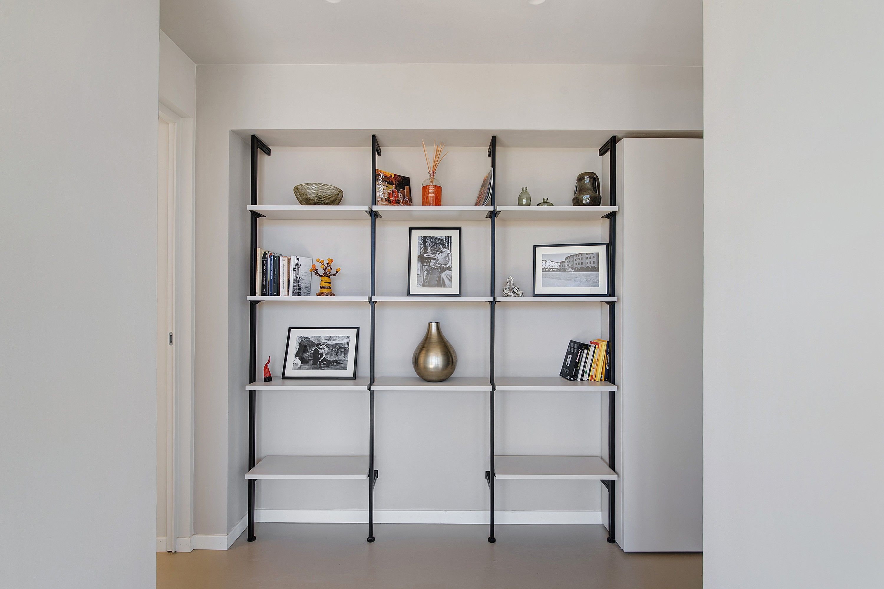 A white shelving unit with various decorative items and framed pictures.