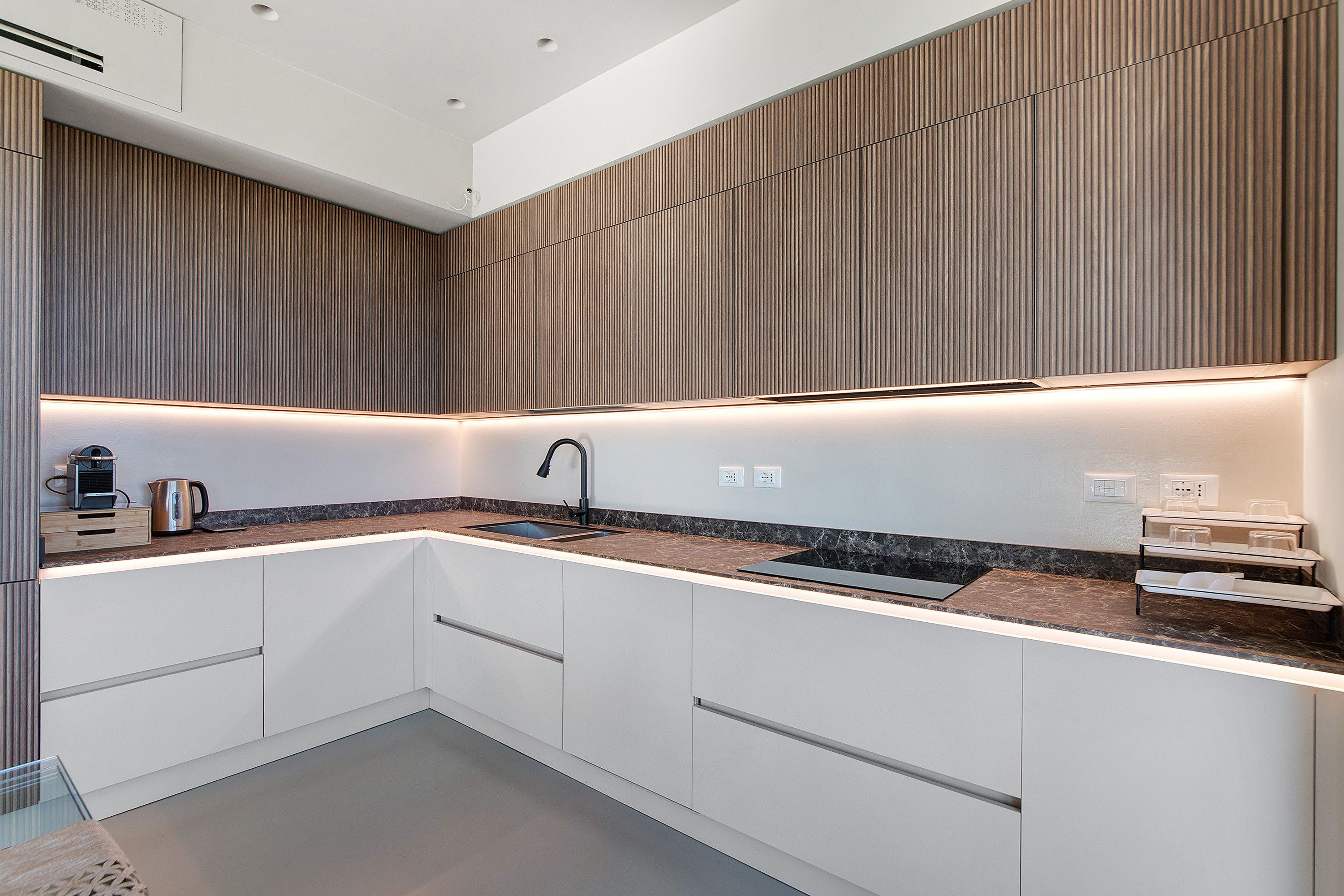 A modern kitchen with a built-in sink, a coffee maker, and a kettle on the countertop.