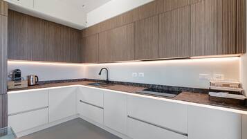 A modern kitchen with a built-in sink, a coffee maker, and a kettle on the countertop.