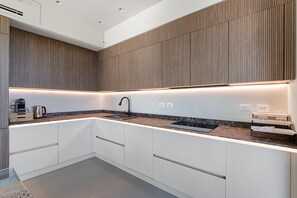 A modern kitchen with a built-in sink, a coffee maker, and a kettle on the countertop.