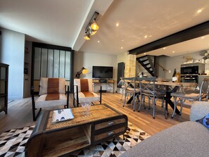 A modern living room with a dining area, a staircase, and a kitchen. - Bois Flotté—downtown—100 meters from the sea—near Bayeux (Port-en-Bessin-Huppain)
