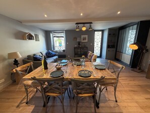 A dining area with a wooden table set for four, surrounded by upholstered chairs. - Bois Flotté—downtown—100 meters from the sea—near Bayeux (Port-en-Bessin-Huppain)