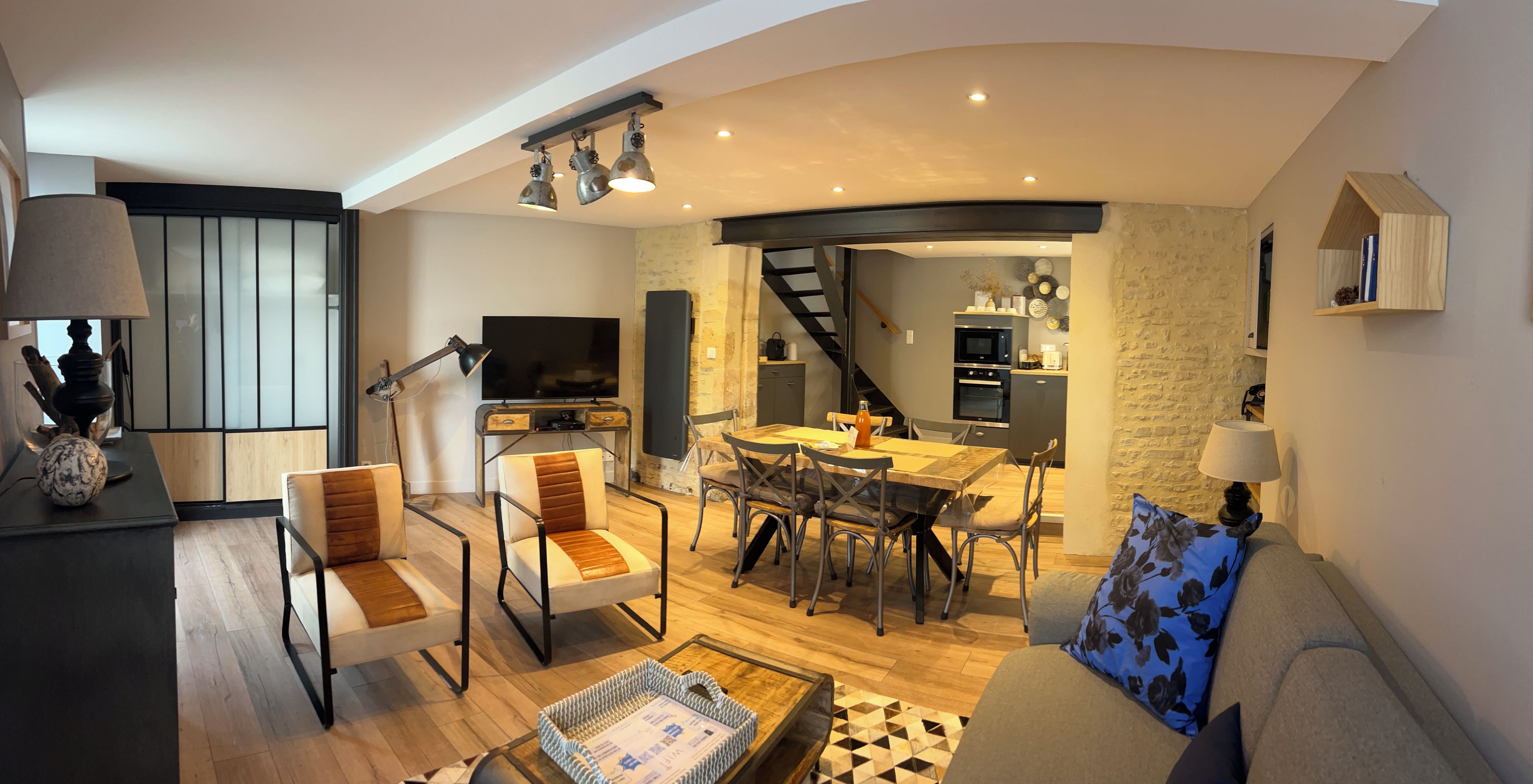 Een moderne woonkamer met een bank, stoelen, een salontafel en een televisie.