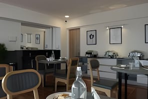 Una zona de menjador moderna amb una taula llarga, cadires i una ampolla d'aigua.
