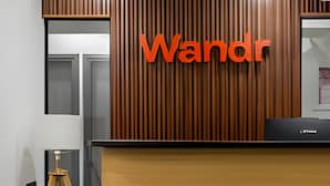 En receptionsdisk med en lodret trævæg og et stort skilt med 'Wandr' på.