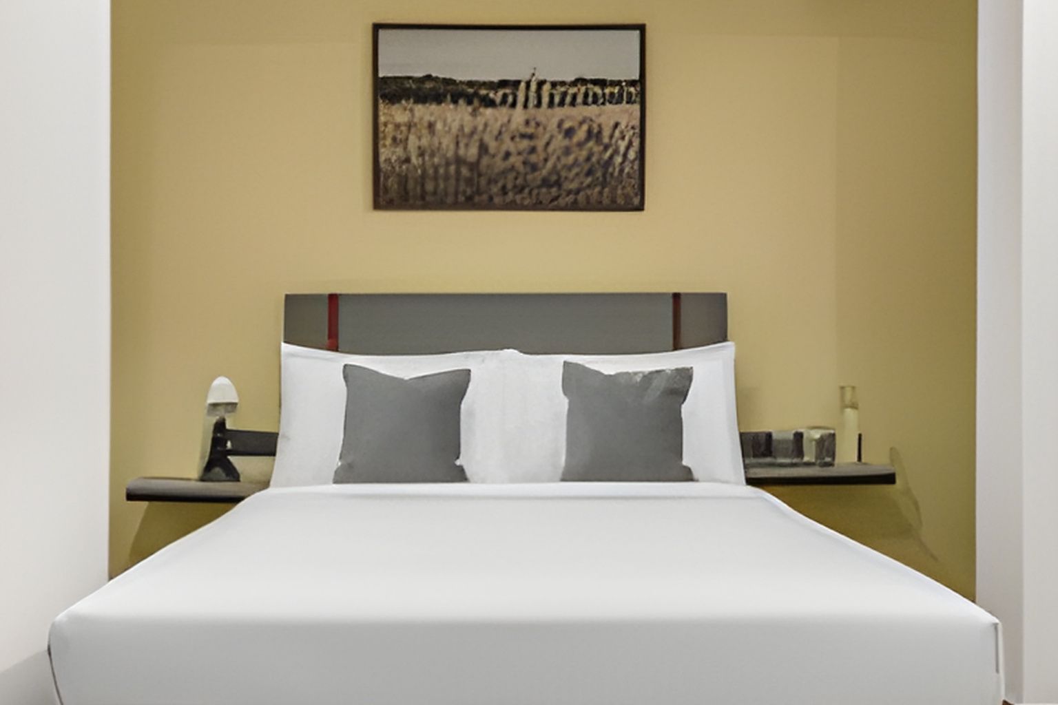 Una habitación de hotel con una cama, una mesita de noche, una lámpara y un cuadro en la pared.