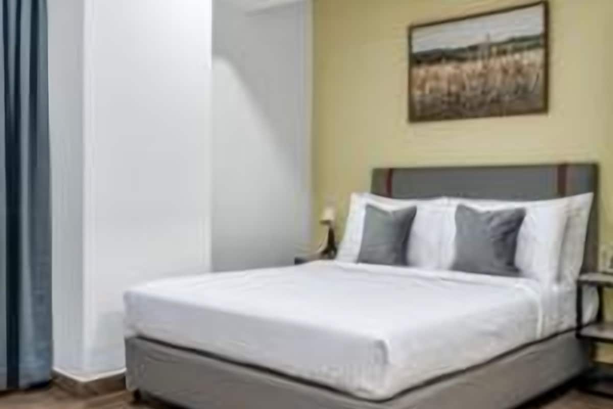 Una habitació d'hotel amb un llit, una taula de nit i un quadre a la paret.