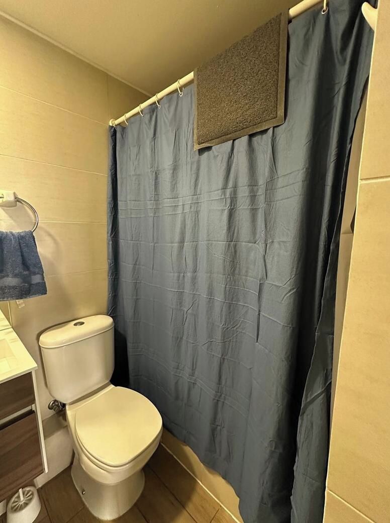 Un bagno con un WC, una tenda da doccia blu e un asciugamano su un portasciugamani.