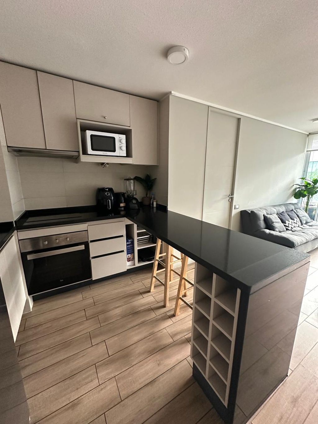 Een moderne keuken met een magnetron, kookplaat en barstoelen.