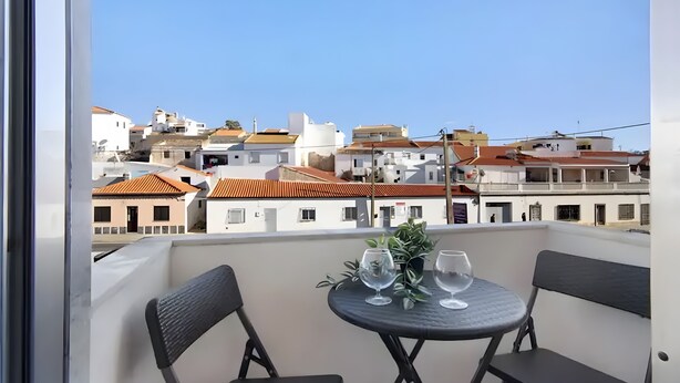 Un balcon avec une table et des chaises, donnant sur un quartier résidentiel composé de différents immeubles.