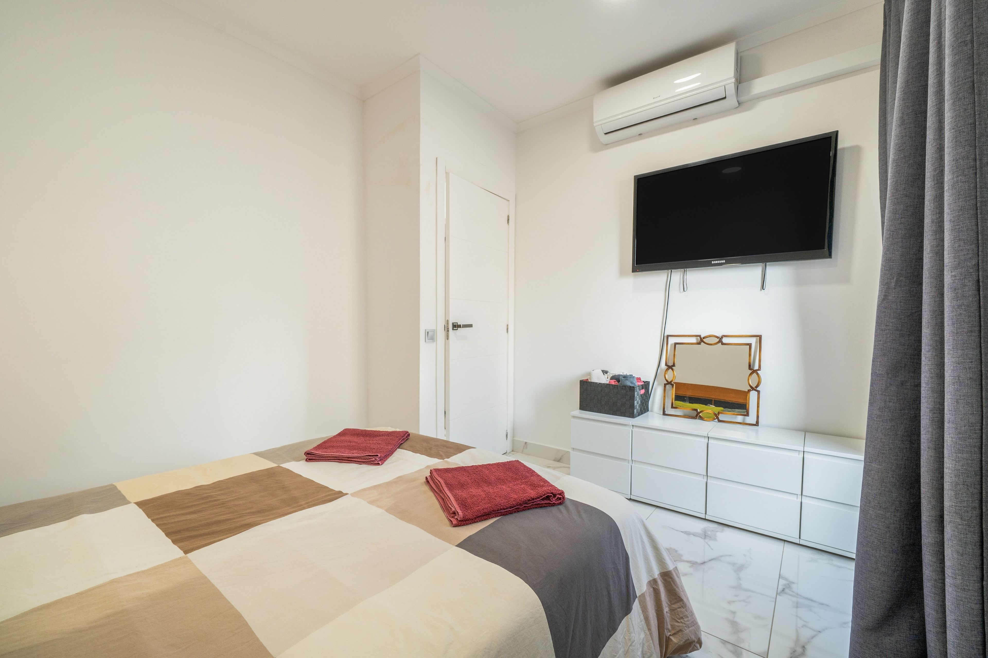 Une chambre d’hôtel équipée d’un lit, d’une télévision, d’un miroir et d’une armoire.