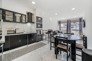 A modern kitchen with black cabinets, a built-in oven, and a microwave. There is a dining area with a round table and chairs.