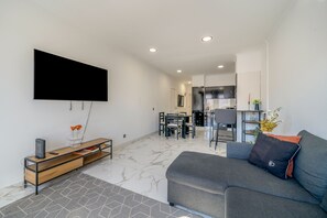 Un salon moderne doté d’un téléviseur à écran plat, d’un canapé, d’un coin repas et d’une cuisine.