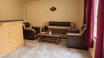 A living room with a sofa, two armchairs, a coffee table, and a wooden cabinet.