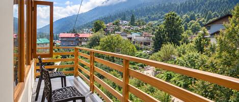 A balcony with a wooden railing, two chairs, and a table.