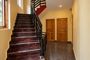 A staircase with dark marble steps and a black railing, leading to a landing with wooden doors.