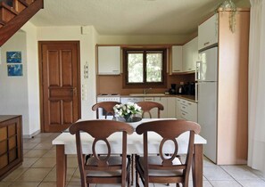 A kitchen with a dining table and chairs, a refrigerator, and a window with blinds. - Villa Paradiso - Your Summer Sanctuary in Sani (Sane)