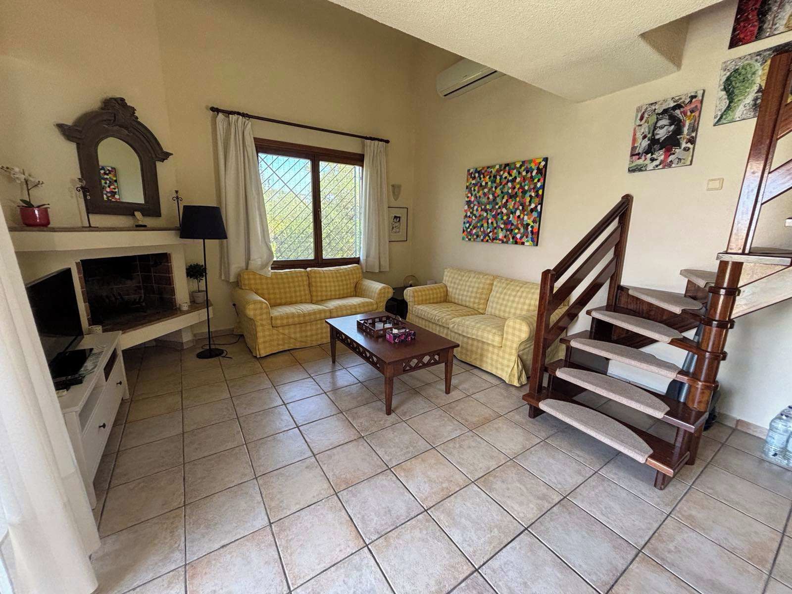 Un salon avec un canapé, une table basse, une cheminée et un escalier.