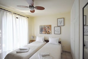 A hotel room with two beds, a ceiling fan, and artwork on the wall. - Villa Paradiso - Your Summer Sanctuary in Sani (Sane)