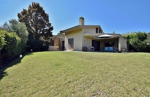 A modern house with a covered patio area, a well-maintained lawn, and a large tree in the background. - Villa Paradiso - Your Summer Sanctuary in Sani (Sane)