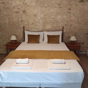 A neatly made bed with a brown headboard, white linens, and two white towels placed on the bed.