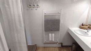 A bathroom with a shower, a sink, and a towel rack.