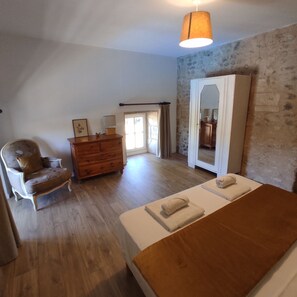 A bedroom with a wooden bed, a dresser, a chair, and a mirror. - Le Pressoir du Château de Clerbise—a spacious, charming vacation rental with a private pool (Belluire)
