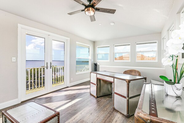Un'ampia stanza con vista sul mare, una ventola a soffitto e un'area pranzo con tavolo e sedie.
