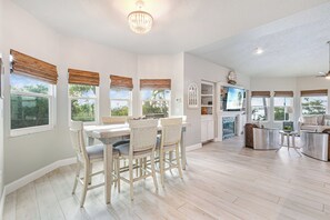 A spacious living area with a dining table, chairs, and a television. - Bees Bungalow - Lux Waterfront Pool & Spa w/ Dock & Lift - 2+ Acres - 360° Views (Matlacha)