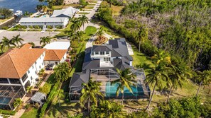 Una proprietà residenziale con una grande piscina, diverse case e vegetazione lussureggiante.
