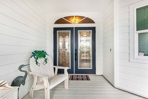 Un portico con una panchina, una poltrona decorativa e un tappetino di benvenuto.