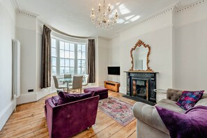 Ein Wohnzimmer mit Kamin, einer Chandelüster und einem großen Spiegel.